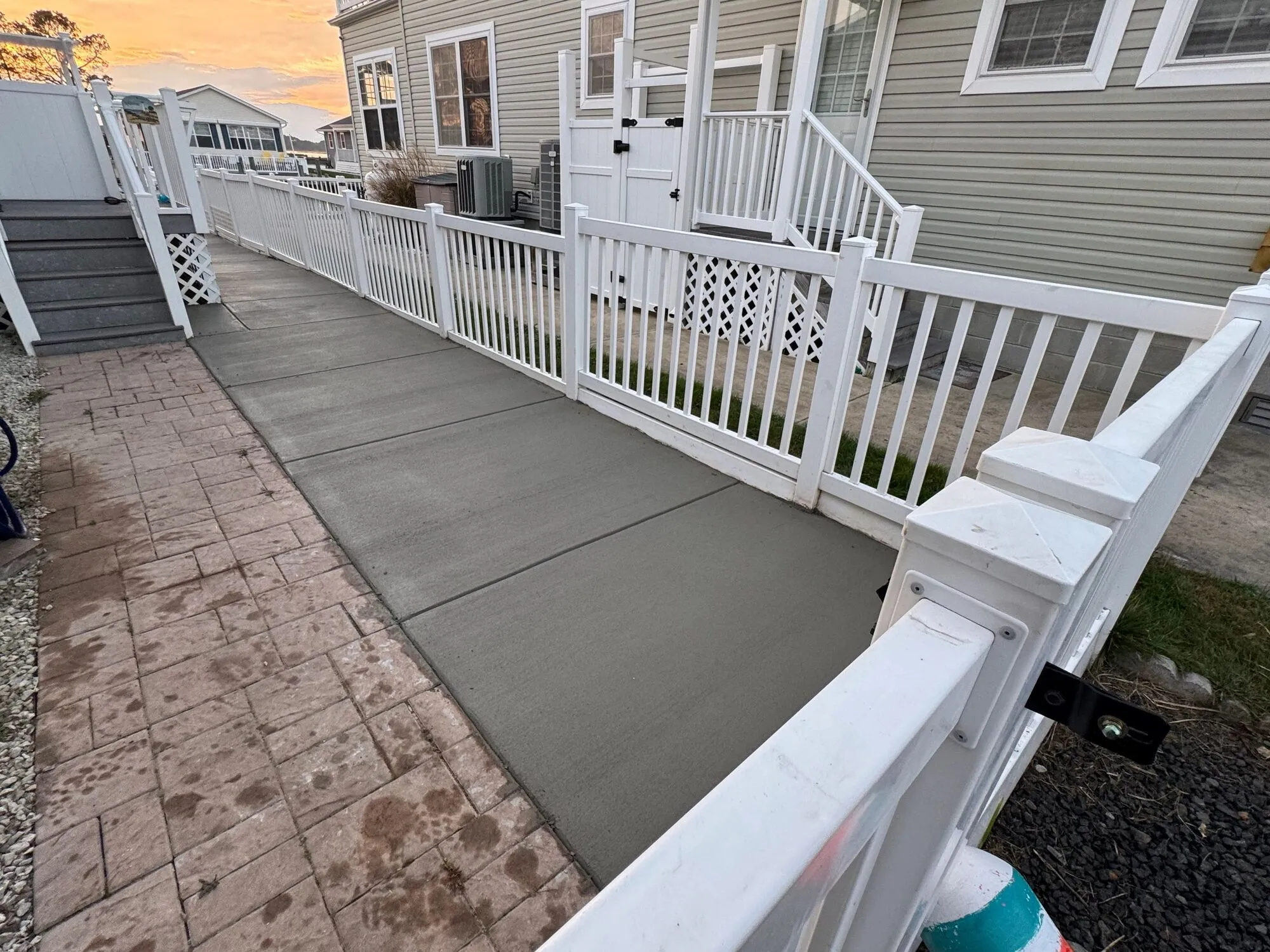 Graded side yard with a new concrete walkway beside a white vinyl fence