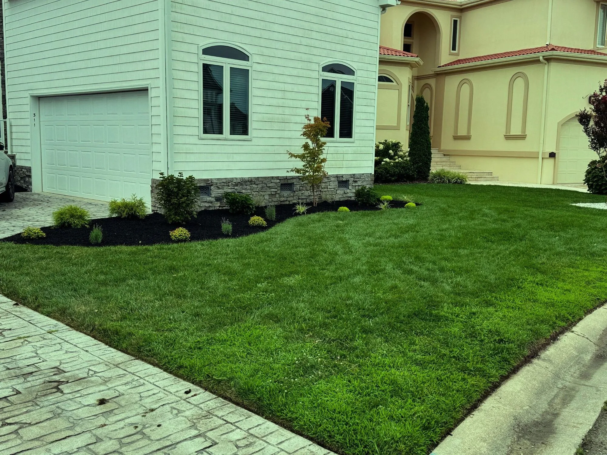 Thick green lawn and fresh planting beds in front of a coastal home